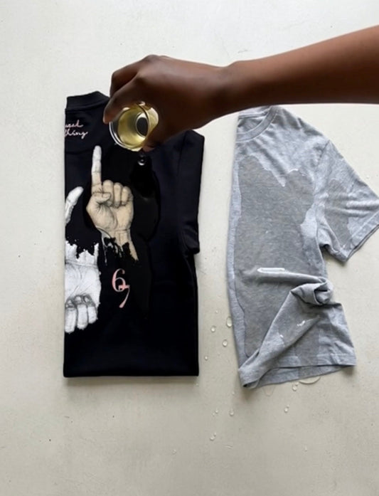 67 Black heavyweight tee having water dripped on it with a cheap grey tee next to it drenched in water.