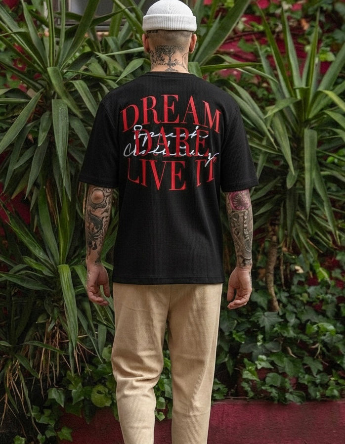 Person wearing a black t-shirt with red text in an outdoor setting