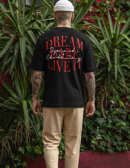 Person wearing a black t-shirt with red text in an outdoor setting