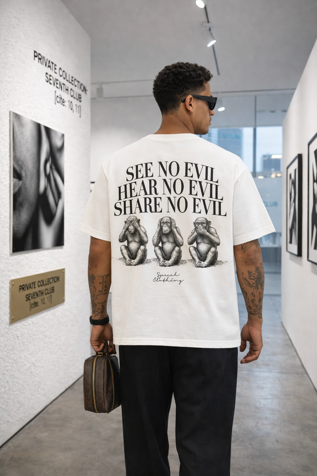 Person wearing a white t-shirt with 'See No Evil, Hear No Evil, Share No Evil' design in an art gallery.