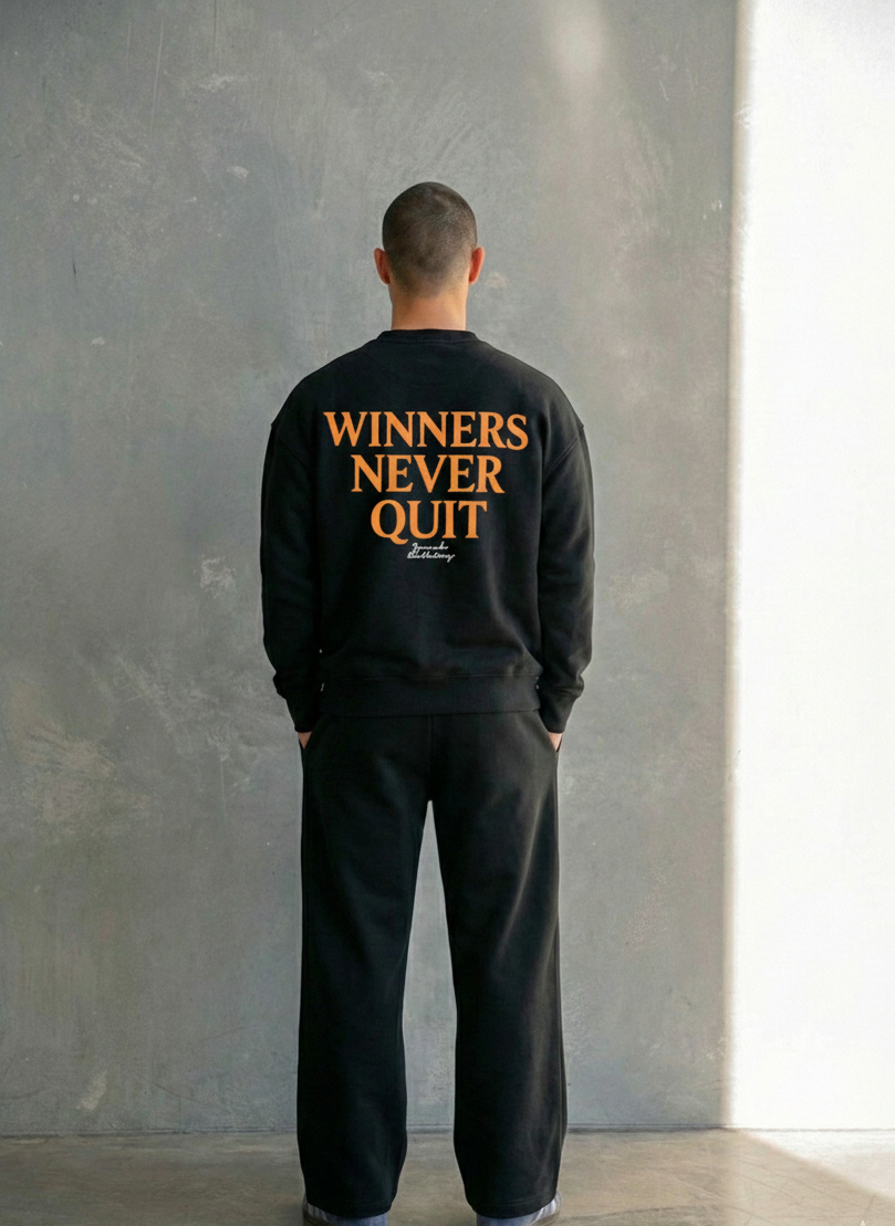 Person wearing a black sweatshirt with 'WINNERS NEVER QUIT' text on the back, standing against a gray wall.