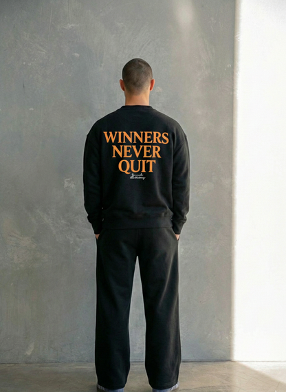 Person wearing a black sweatshirt with 'WINNERS NEVER QUIT' text on the back, standing against a gray wall.