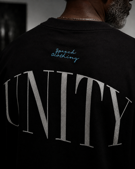 Close-up back view of a person wearing a black T-shirt with large metallic silver 'UNITY' lettering and small blue script text reading 'Speech Clothing' near the upper back.