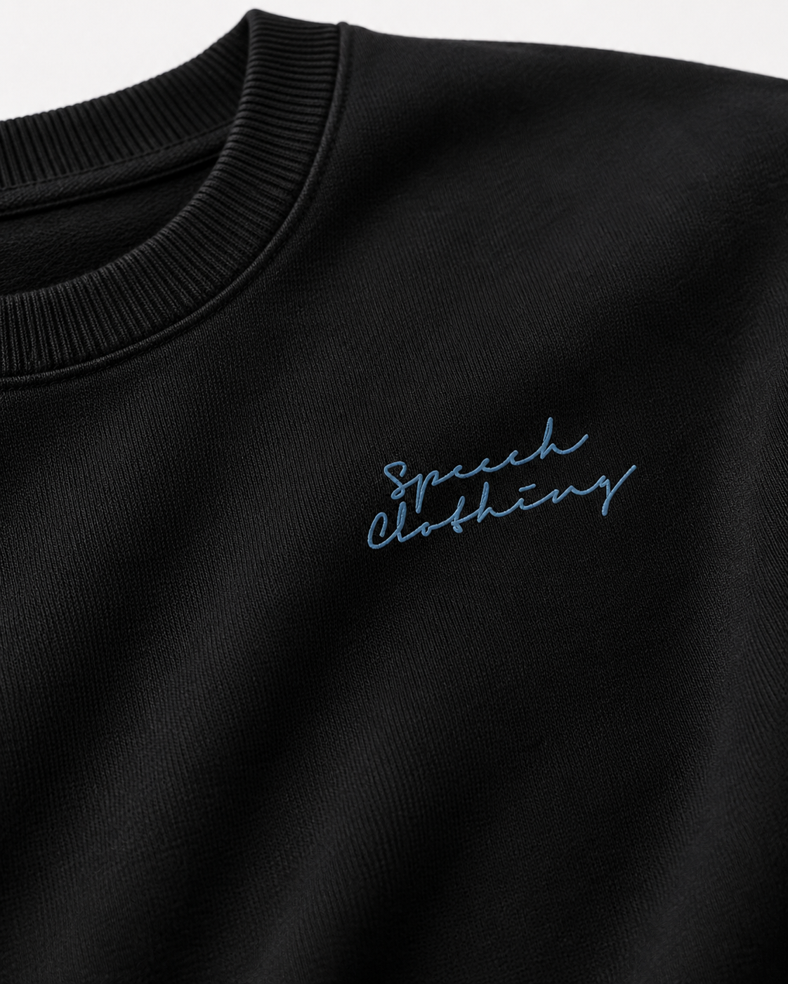 Close-up of a black crewneck sweatshirt featuring light blue embroidered script reading 'Speech clothing' on the chest.