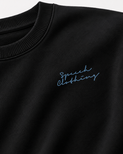 Close-up of a black crewneck sweatshirt featuring light blue embroidered script reading 'Speech clothing' on the chest.