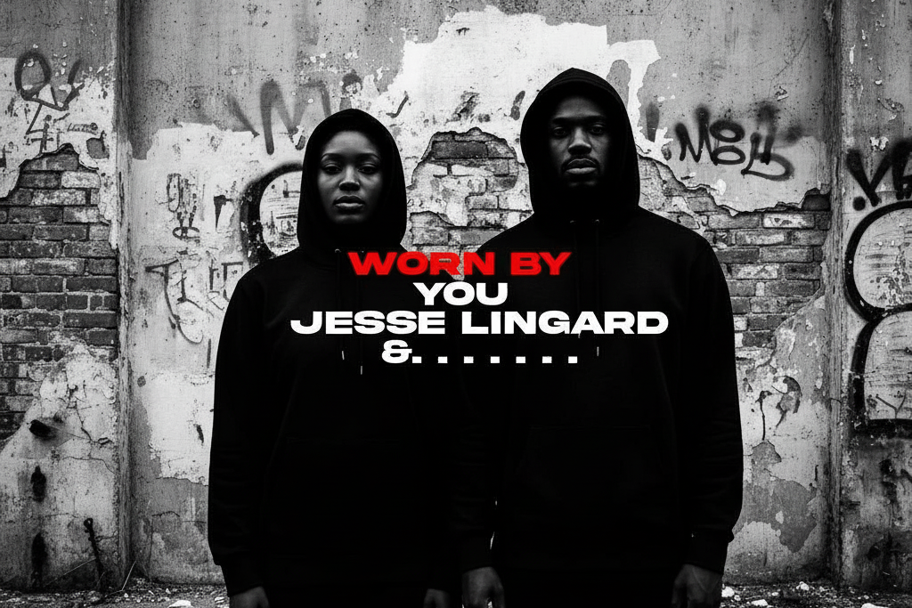 Two people wearing black hoodies with text in front of a graffiti-covered wall.
